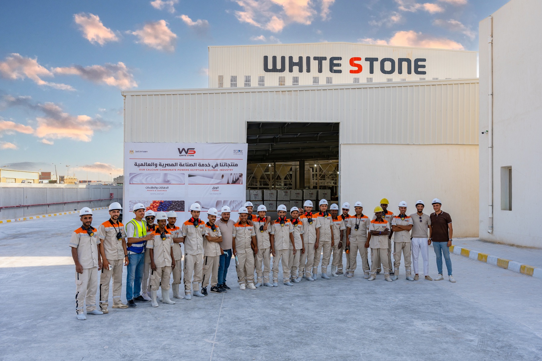 The full White Stone team in branded uniforms and hard hats, lined up in front of the plant at Ain Sokhna